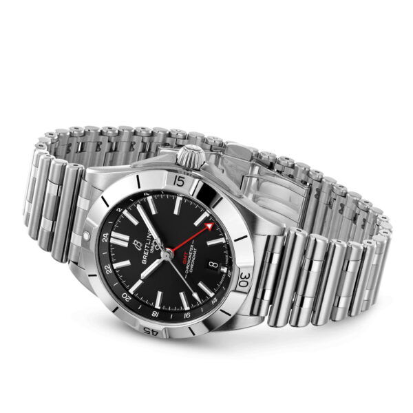 Die Breitling Chronomat Automatic GMT 40 besticht durch ein schwarzes Zifferblatt mit weißen Stundenmarkierungen, Zeigern und einem roten Zeiger mit Pfeilspitze. Sie verfügt über Markendetails, zusätzlichen Text und eine Datumsanzeige auf der Drei-Uhr-Position auf dem silbernen Metallarmband.