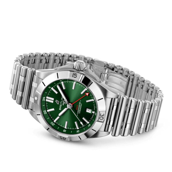 Die Breitling Chronomat Automatic GMT 40 ist eine Edelstahluhr mit silbernem Metallgliederarmband, grünem Zifferblatt, silbernen Stundenmarkierungen und einem Sekundenzeiger mit roter Spitze. Sie trägt den Markennamen und das Logo auf dem Zifferblatt und verfügt über ein Datumsfenster bei 3 Uhr.