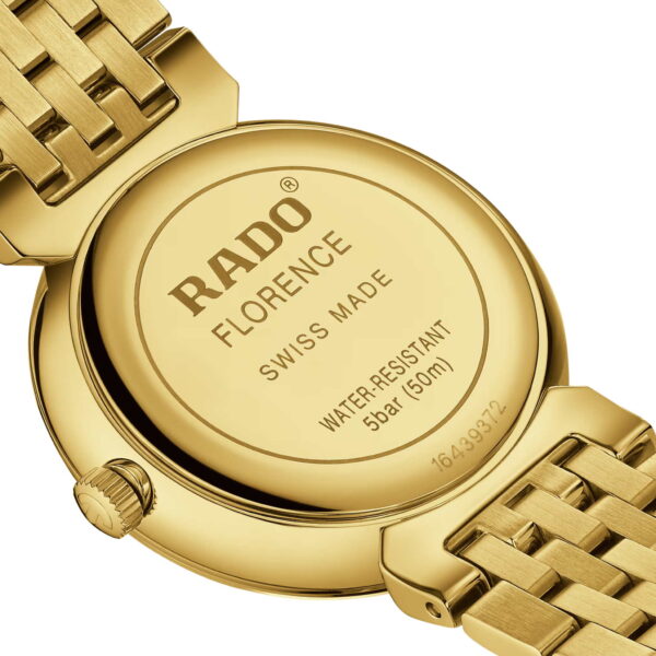 Nahaufnahme der Rückseite einer Rado Florence Diamonds-Uhr, Gold mit der Gravur „Rado Florence, Swiss Made, Water-Resistant 5 Bar (50 m)“, mit einem dicht gewebten Goldband und sichtbarer Schließe.