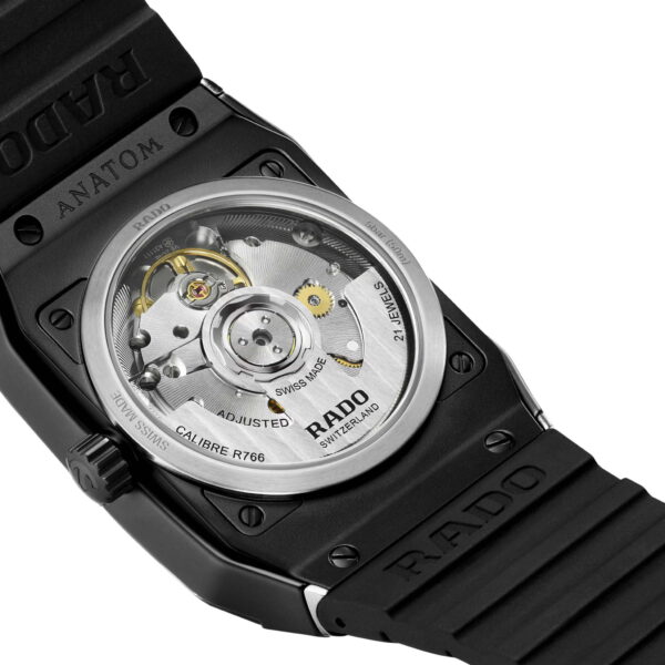 Nahaufnahme der Rado Anatom Automatic Uhr in Schwarz mit transparenter Rückseite, die den Blick auf das komplexe Automatikwerk freigibt. Sichtbare Details sind der Aufzugsrotor und der eingravierte Text. Das schwarze Kautschukarmband ist ein Blickfang.