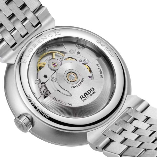 Nahaufnahme einer Rado Florence Automatic Armbanduhr, deren innere Mechanismen durch einen transparenten Gehäuseboden sichtbar sind. Diese silberne Uhr verfügt über ein Edelstahlarmband mit Gravuren, die Angaben zur Wasserdichtigkeit und zum Uhrwerktyp enthalten.