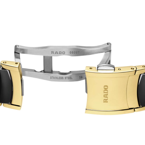 Nahaufnahme einer Uhrschließe aus der Rado Centrix Diamonds Serie. Ein Faltmechanismus aus poliertem Edelstahl ist mit einem Armband aus goldenen und schwarzen Segmenten gepaart, wobei auf einem Segment der Markenname eingraviert ist.
