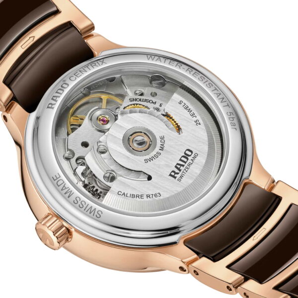 Nahaufnahme der Rückseite einer Luxusuhr mit raffinierter Mechanik. Das Armband ist in Roségold und Schwarz gehalten. Die Rückseite trägt die Inschrift „Rado Centrix Automatic Diamonds“ und ist mit Swiss-Made-Markierungen versehen.