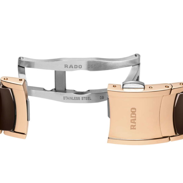 Das Armband der Rado Centrix Automatic Diamonds-Uhr ist mit glänzenden goldenen und dunkelbraunen Gliedern versehen und verfügt über eine teilweise geöffnete „RADO“-Schließe aus Edelstahl, die Inschriften und Details freigibt.