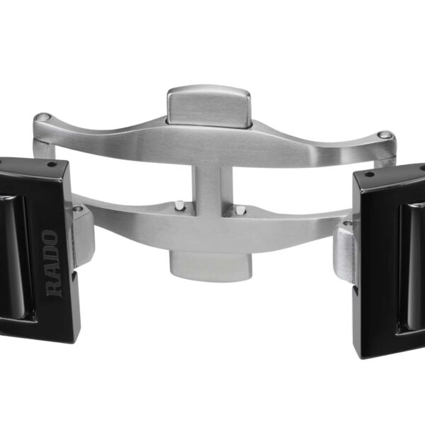 Nahaufnahme der Edelstahl-Schmetterlingsschließe eines Rado True Round Automatic Open Heart Uhrenarmbands. Das glänzende Metall kontrastiert mit den glänzend schwarzen Keramikgliedern mit der Gravur „RADO“. Die geöffnete Schließe gibt den Blick auf ihren sicheren Verschluss frei.
