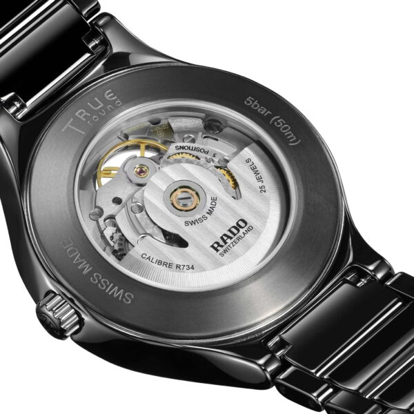 Eine Nahaufnahme der Rado True Round Automatic Open Heart Uhr zeigt ein transparentes Gehäuse, das den Blick auf komplexe mechanische Uhrwerke freigibt. Das Edelstahlarmband ist sichtbar und trägt die Gravuren „Swiss Made“ und „RADO“.