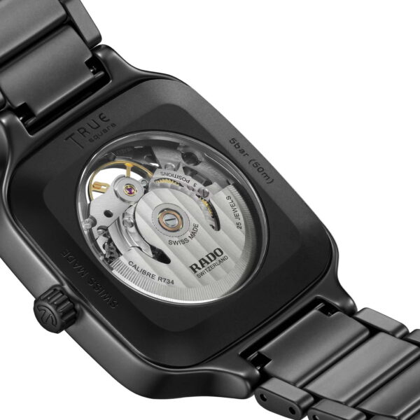 Die Rado True Square Automatic Skeleton ist eine Nahaufnahme ihrer schwarzen Armbanduhr mit transparentem Gehäuseboden, der den komplizierten inneren Mechanismus und ein Metallgliederarmband freigibt und Markendetails auf dem inneren Uhrwerk anzeigt.
