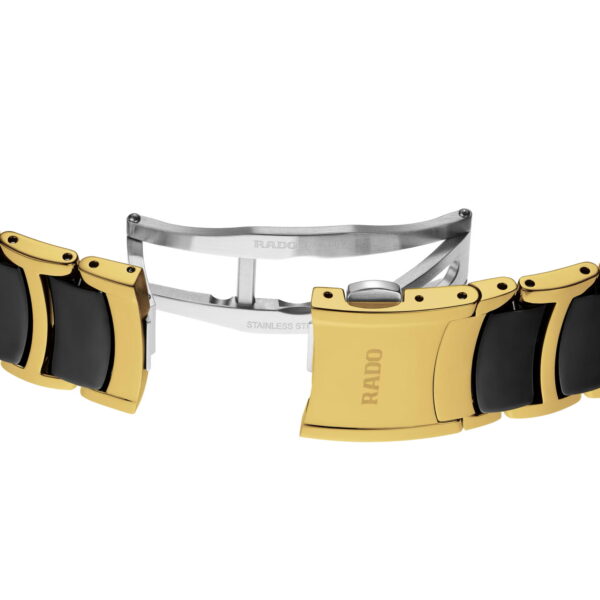 Nahaufnahme des Armbandverschlusses der Rado Centrix Diamonds. Er zeigt goldene und schwarze Glieder mit einem Klappmechanismus aus Edelstahl. Der goldene Verschluss ist mit dem Markennamen RADO graviert.