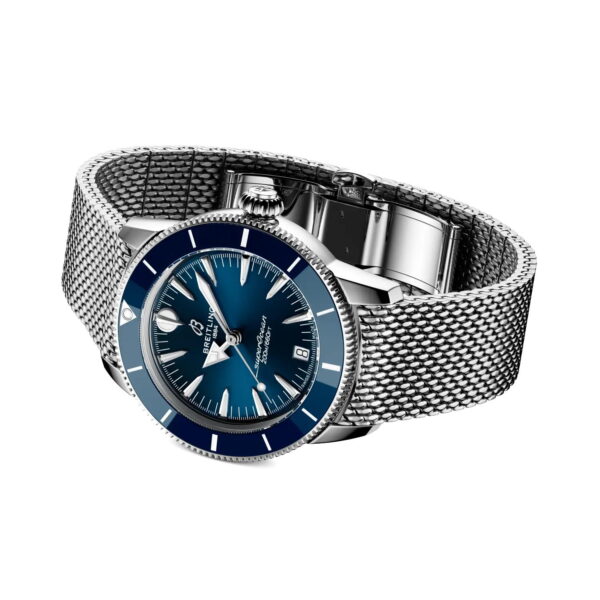 Die Breitling Superocean Heritage Automatic 36 wird schräg auf weißem Hintergrund dargestellt und verfügt über ein blaues Zifferblatt und eine blaue Lünette, silberne Stundenmarkierungen, eine Datumsanzeige und ein Edelstahl-Mesh-Armband.
