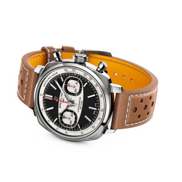Die Breitling Top Time B01 Racing ist eine luxuriöse Chronometeruhr mit braunem, perforiertem Lederarmband, schwarzem Zifferblatt, grünen Leuchtindexen und silbernen Chronographenzifferblättern auf dunklem Hintergrund.