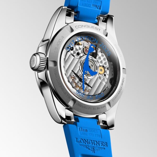 Eine Nahaufnahme des Uhrenbodens der Longines Conquest offenbart das mechanische Uhrwerk, die gravierten Details und die Zahnräder durch einen transparenten Gehäuseboden, ergänzt durch ein leuchtend blaues Silikonarmband.