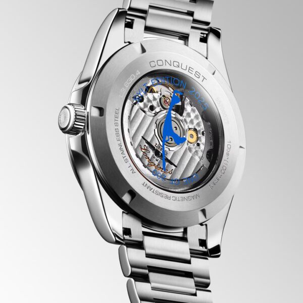 Eine Nahaufnahme der Longines Conquest Edelstahlarmbanduhr zeigt ihr mechanisches Uhrwerk durch einen transparenten Gehäuseboden, auf dem "Conquest", "Edition 2023" und "Magnetic Resistant" eingraviert sind.