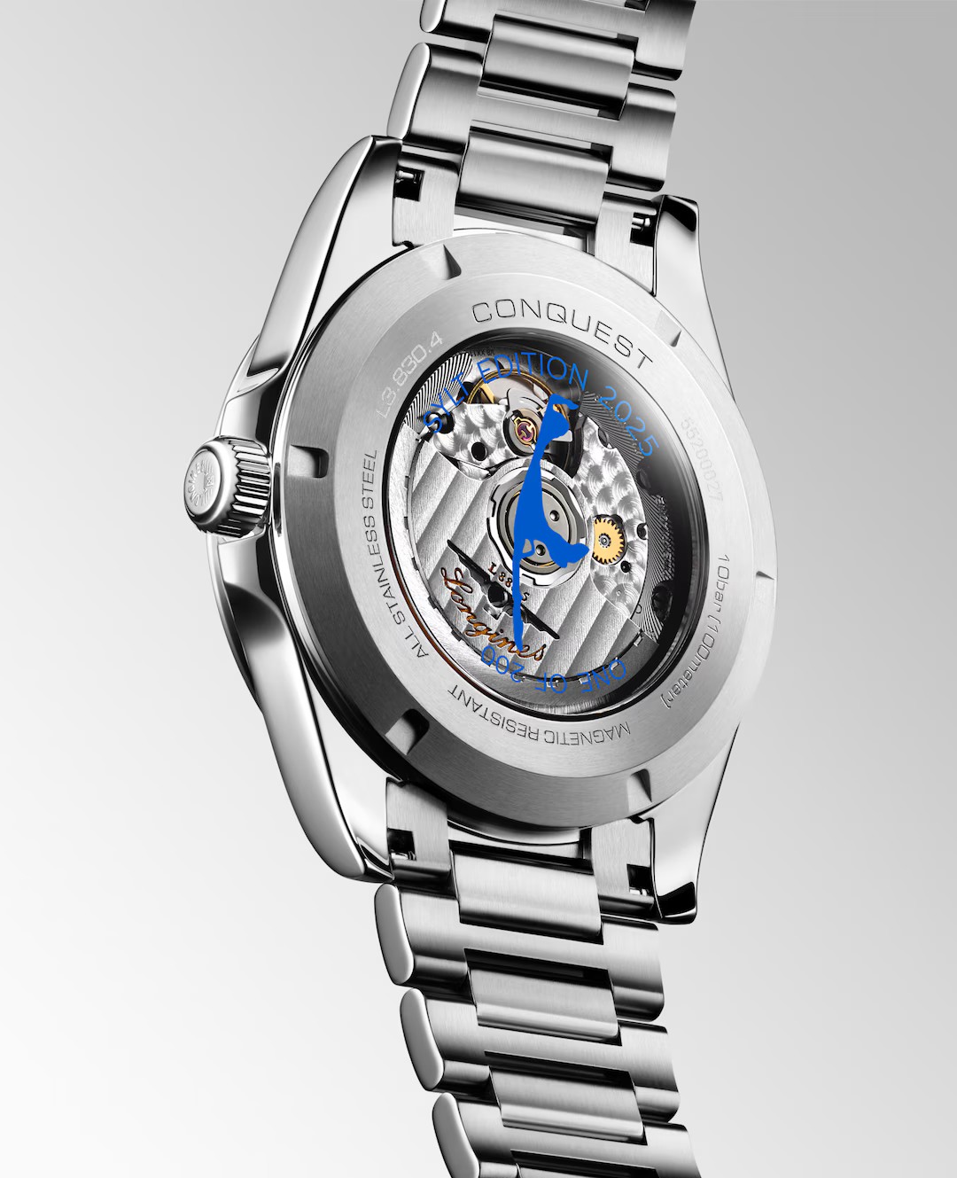 Eine Nahaufnahme der Longines Conquest Edelstahlarmbanduhr zeigt ihr mechanisches Uhrwerk durch einen transparenten Gehäuseboden, auf dem "Conquest", "Edition 2023" und "Magnetic Resistant" eingraviert sind.