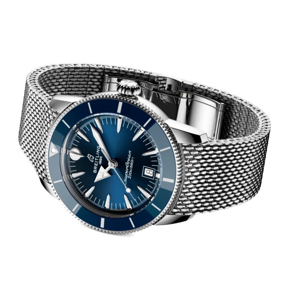 Die Breitling Superocean Heritage B31 Automatic 42 verfügt über ein blaues Zifferblatt, eine Datumsanzeige und ein silbernes Metallarmband aus Mesh, das schräg auf einem weißen Hintergrund angebracht ist.