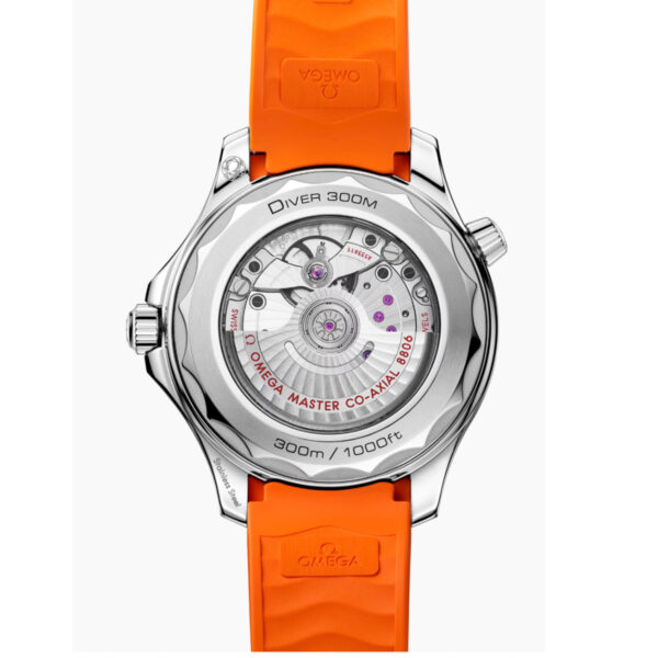 Nahaufnahme des transparenten Gehäusebodens der OMEGA Seamaster Diver 300M mit orangefarbenem Kautschukarmband, auf dem das komplizierte Uhrwerk und die Gravuren zu sehen sind: "Diver 300M" und "OMEGA MASTER CO-AXIAL 8800".