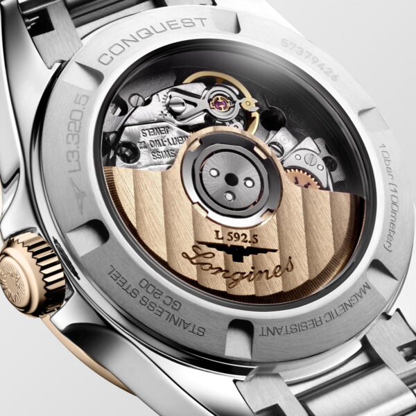 Nahaufnahme des Bodens der Longines Conquest, auf dem das freiliegende Automatikwerk mit Goldrotor, gravierten Details und Edelstahlgehäuse zu sehen ist. Der komplizierte Uhrenmechanismus ist deutlich sichtbar.
