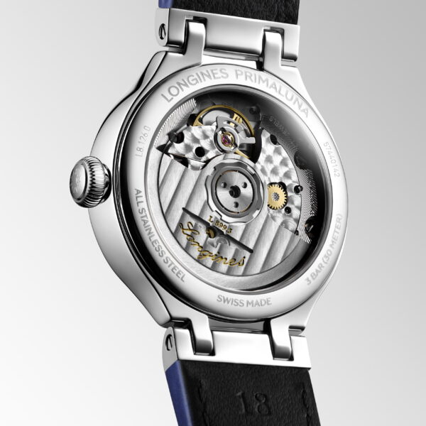 Nahaufnahme des Bodens der Longines Primaluna Moonphase, die durch einen transparenten Gehäuseboden ihr mechanisches Uhrwerk offenbart, mit gravierten Details und einem sichtbaren schwarzen Lederarmband.