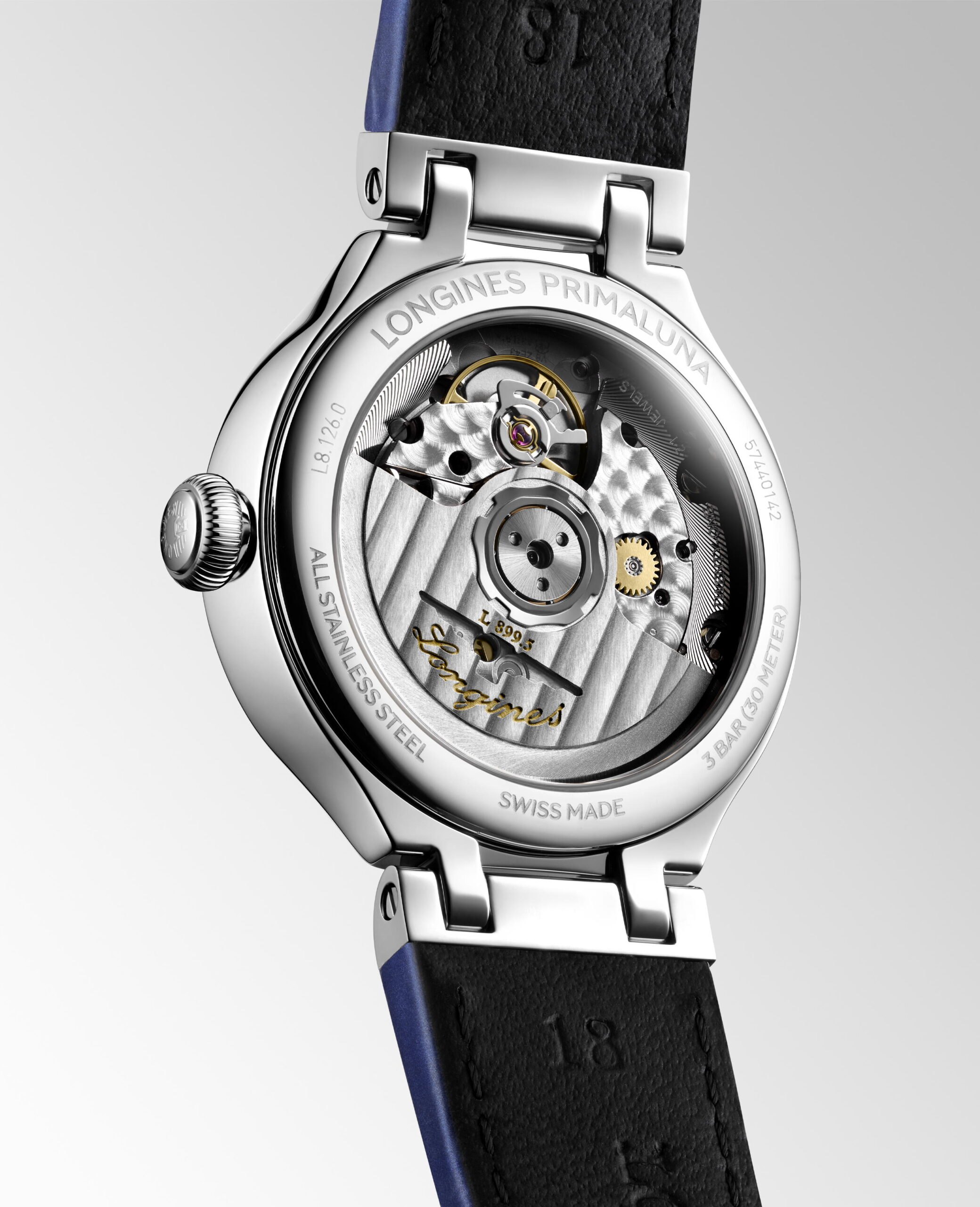 Nahaufnahme des Bodens der Longines Primaluna Moonphase, die durch einen transparenten Gehäuseboden ihr mechanisches Uhrwerk offenbart, mit gravierten Details und einem sichtbaren schwarzen Lederarmband.