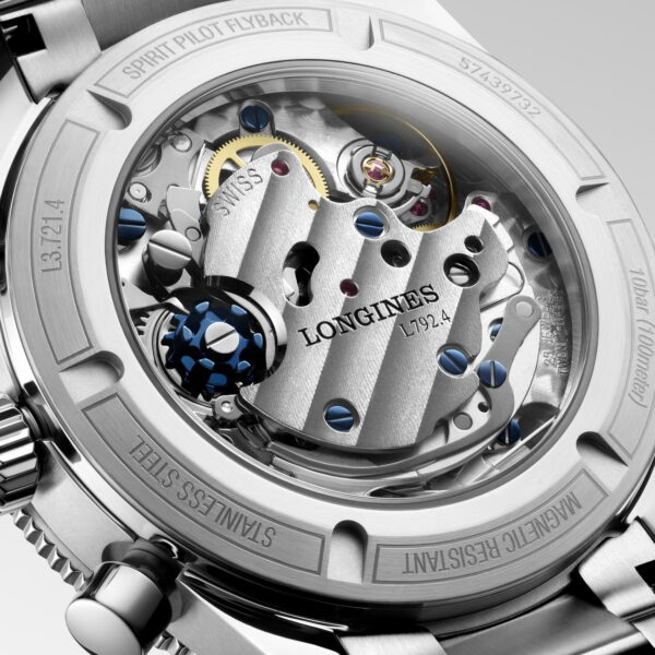 Nahaufnahme der Rückseite einer Longines Spirit Flyback, die das komplizierte mechanische Uhrwerk mit sichtbaren Zahnrädern, Schrauben und eingraviertem Text auf dem Metallgehäuse und den Komponenten zeigt.