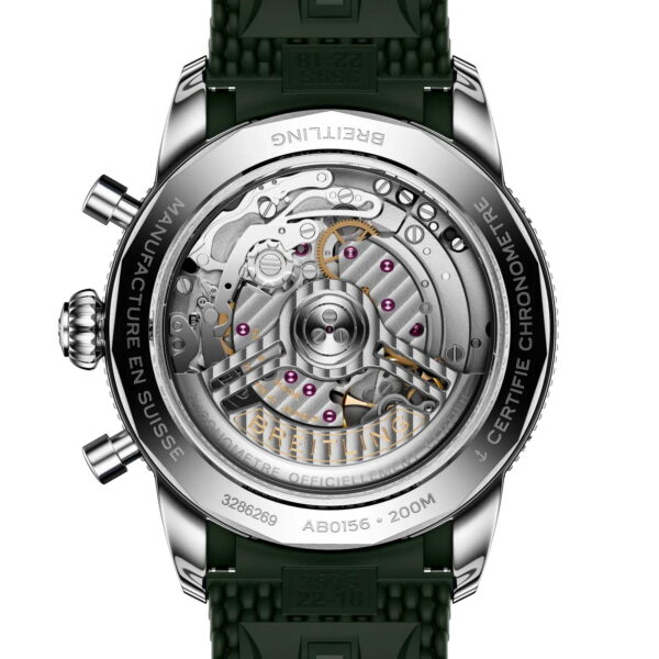 Nahaufnahme des Bodens der Breitling Superocean Heritage B01 Chronograph 42, auf dem das transparente Gehäuse mit den sichtbaren Zahnrädern zu sehen ist. Das silberne Gehäuse hat einen eingravierten Text und ist mit einem grün strukturierten Kautschukarmband versehen.