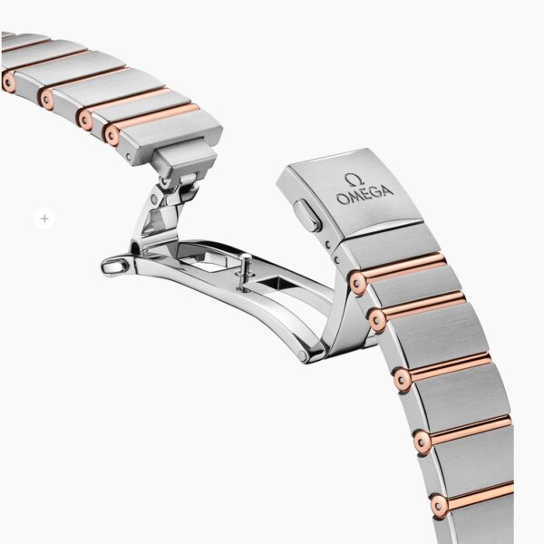 Nahaufnahme der Schließe des OMEGA Constellation Manhattan Armbands mit Gliedern aus Edelstahl und Roségold und dem eingravierten OMEGA-Logo auf der Schließe vor einem weißen Hintergrund.