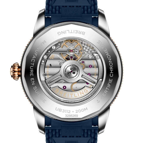 Nahaufnahme des transparenten Gehäusebodens der Breitling Superocean Heritage B31 Automatic 44 mit ihrem komplizierten mechanischen Uhrwerk, den gravierten Details und dem blauen Armband, das am Gehäuse aus Silber und Roségold befestigt ist.