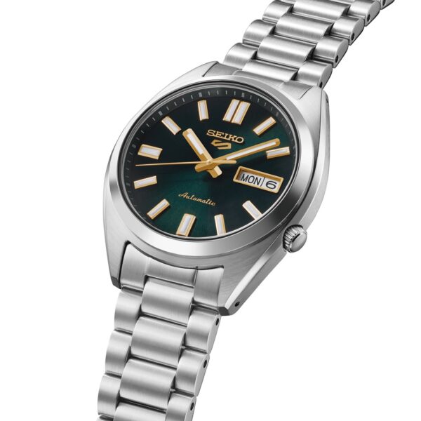 Die SNX SEIKO 5 Automatik verfügt über ein Edelstahlgehäuse, ein grünes Zifferblatt, goldene und weiße Indexe, silberne Zeiger, eine Datumsanzeige (Montag der 6.) und ein Metallgliederarmband.