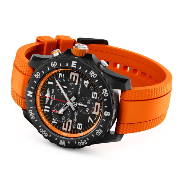 Die Breitling Professional Endurance Pro 44 ist eine schwarze Chronographenuhr mit schwarzer Lünette, orangefarbenen Akzenten und einem orangefarbenen, strukturierten Kautschukarmband, das schräg auf einem weißen Hintergrund abgebildet ist.
