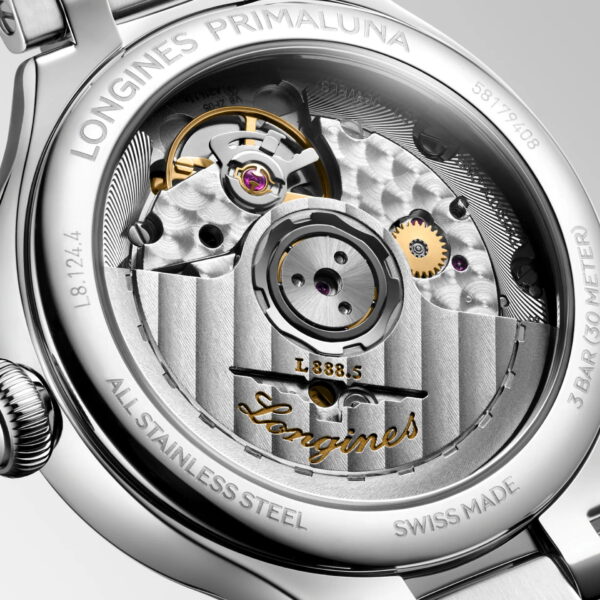 Nahaufnahme des Edelstahl-Gehäusebodens der Longines Primaluna, auf dem gravierte Details, sichtbare Zahnräder und der goldene Markenname zu sehen sind, die das komplizierte mechanische Uhrwerk hervorheben.