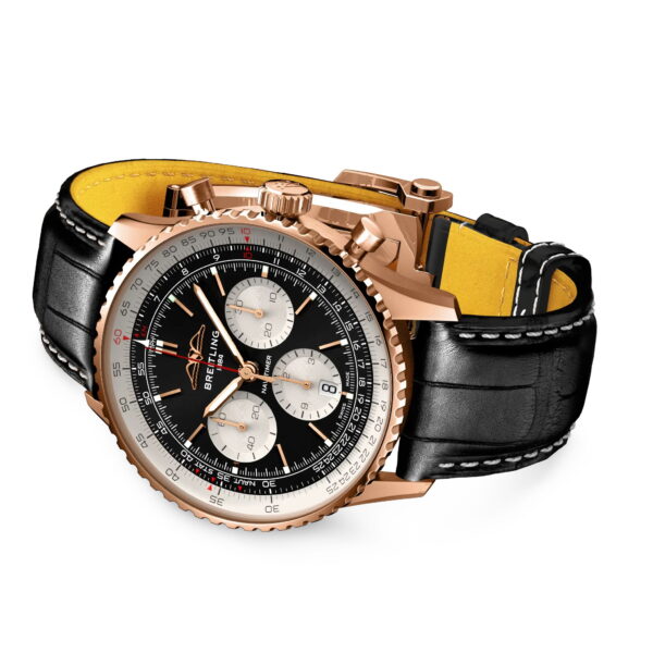 Die Breitling Navitimer B01 Chronograph 43 verfügt über ein schwarzes Zifferblatt mit drei silbernen Hilfszifferblättern, ein Gehäuse aus Roségold und ein schwarzes Lederarmband mit gelbem Futter, das schräg auf einem weißen Hintergrund angebracht ist.