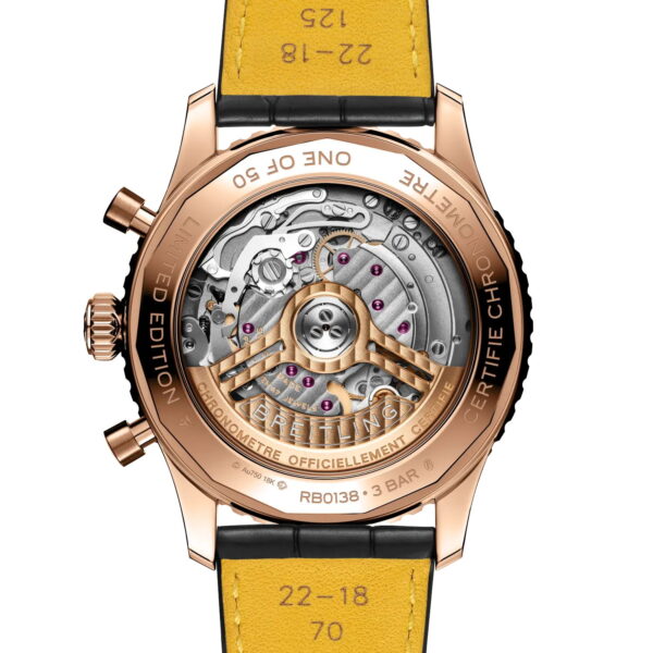 Das Bild zeigt die Rückseite einer Breitling Navitimer B01 Chronograph 43 mit einem transparenten Goldgehäuse, das den Blick auf detaillierte mechanische Zahnräder freigibt. Auf dem gravierten Gehäuse und dem gelben Lederarmband sind Zahlen und Größenangaben zu sehen.