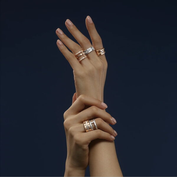 Zwei Hände mit manikürten Nägeln sind elegant vor einem dunklen Hintergrund posiert, jede geschmückt mit dem Chopard Ice Cube Ring Weite 57 in Gold- und Silbertönen, die teilweise mit eingebetteten Diamanten funkeln.