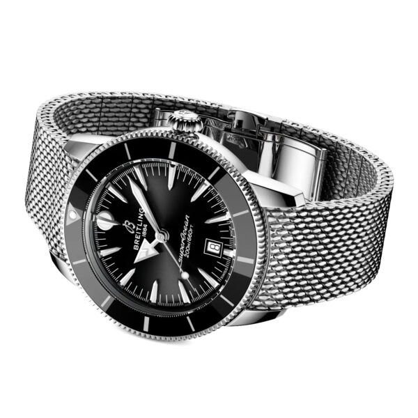 Eine Breitling Superocean Heritage B31 Automatic 44 Armbanduhr mit silbernem Gehäuse, schwarzem Zifferblatt, silbernen Indexen, Datumsfenster und strukturiertem Metallgewebeband, schräggestellt auf weißem Hintergrund.