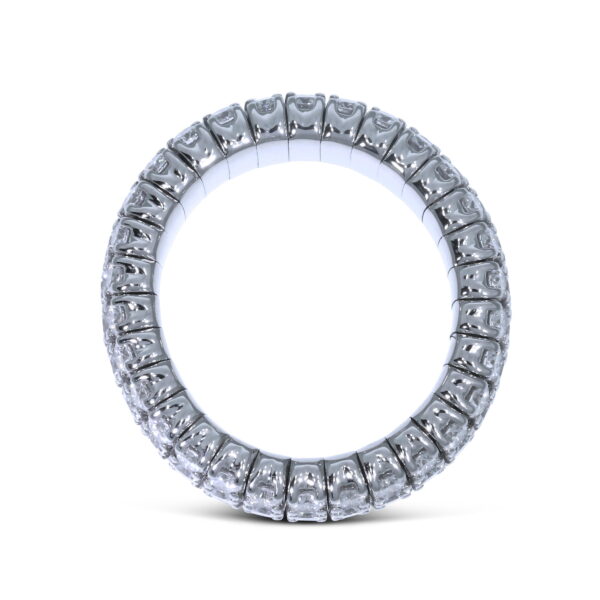 Der Scheffel Stretch Griff Ring zeichnet sich durch eine durchgehende Reihe klarer, rund geschliffener Edelsteine aus, die um ein silbernes Band herum gefasst sind und aufrecht auf einem weißen Hintergrund stehen.