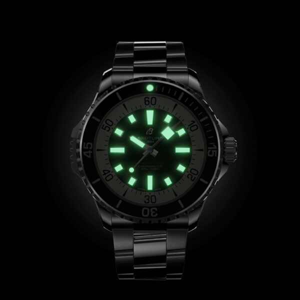 Eine schwarze Breitling Superocean III Automatic 46 Armbanduhr mit Metallband wird im Dunkeln gezeigt, wobei die grün leuchtenden Zeiger und Indexe das Zifferblatt vor dem schwarzen Hintergrund erhellen.