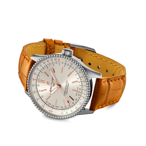 Eine Breitling Navitimer Automatic 35 Armbanduhr in Silber mit weißem Zifferblatt, orangefarbenen Markierungen und braunem Alligatorlederarmband, schräggestellt auf weißem Hintergrund.