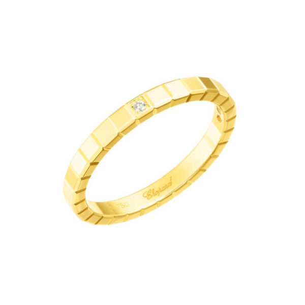 Der Chopard Ring Ice Cube Weite 53 besteht aus einem geometrisch strukturierten Goldband mit einem kleinen zentralen Diamanten und dem eingravierten Schriftzug "Chopard". Auf einem weißen Hintergrund dargestellt.