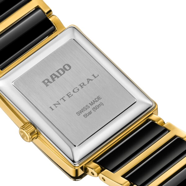 Nahaufnahme der Rückseite einer Rado Integral Diamonds Armbanduhr mit einem Edelstahlgehäuse mit eingraviertem Schriftzug und technischen Daten sowie einem goldfarbenen und schwarzen Keramikgliederband.