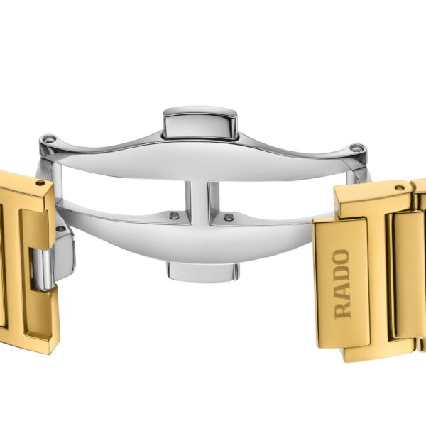Nahaufnahme des Rado Integral Diamonds Armbands mit goldenen und schwarzen Gliedern und einer offenen silbernen Faltschließe. "RADO" ist auf einem goldenen Glied auf der rechten Seite eingraviert.