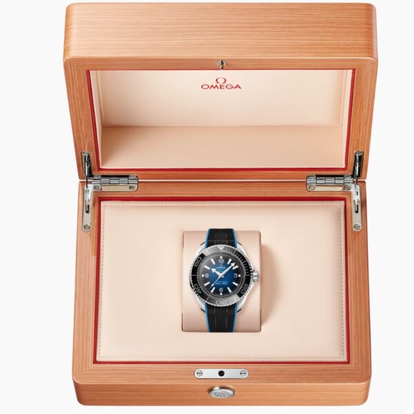 Die OMEGA Seamaster Planet Ocean Ultra Deep mit blauem Zifferblatt und schwarzem Armband wird in einer offenen Box aus hellem Holz mit cremefarbener Innenausstattung und dem Omega-Logo auf dem Deckel präsentiert.