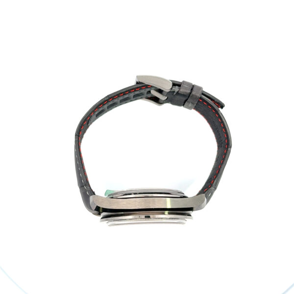 Die OMEGA Speedmaster Grey Side of the Moon ist von der Seite mit ihrem schwarzen Armband mit roter Naht und der Dornschließe im oberen Bereich zu sehen; das Zifferblatt ist nicht sichtbar.