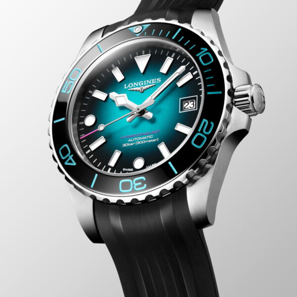 Die Longines HydroConquest Commonwealth Games 2026, eine Taucheruhr aus Edelstahl mit tealfarbenem Zifferblatt, schwarzer Lünette, großen weißen Indexen, Datum bei 3 Uhr und schwarzem Kautschukarmband, wird schräg auf einem hellgrauen Hintergrund angezeigt.