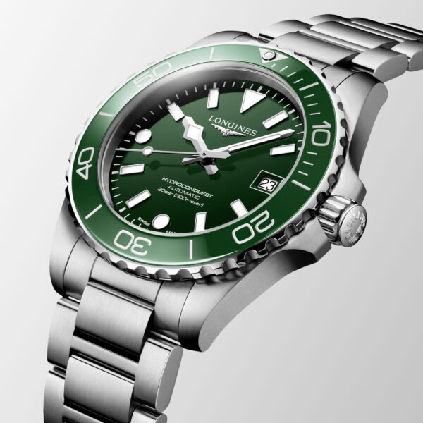 Eine Nahaufnahme der Longines HydroConquest Armbanduhr zeigt ein Edelstahlgehäuse, eine grüne Lünette und ein grünes Zifferblatt, silberne Markierungen und Zeiger sowie ein Metallarmband auf einem hellgrauen Hintergrund.