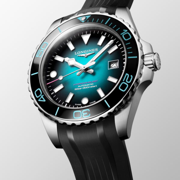 Eine Nahaufnahme der Longines HydroConquest Commonwealth Games 2026 Uhr mit teal-schwarzem Zifferblatt mit Farbverlauf, auffälligen weißen Indexen, Datumsfenster bei 3 Uhr, silberner Lünette und schwarzem Kautschukarmband vor hellem Hintergrund.