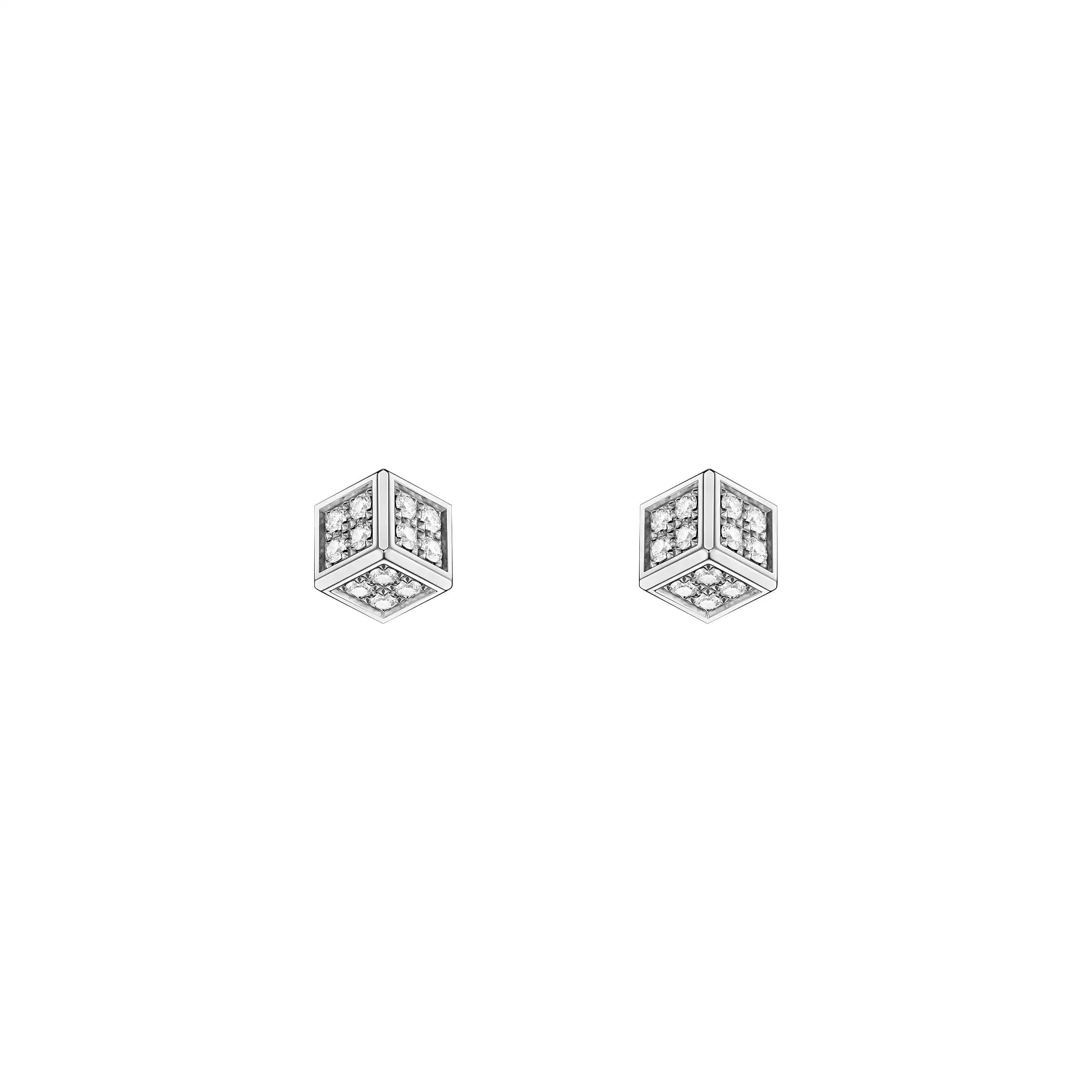 Bei den „Ice Cube be Cube“-Ohrsteckern von Chopard handelt es sich um silberfarbene, würfelförmige Ohrstecker, deren Seiten jeweils mit kleinen funkelnden Steinen verziert sind; abgebildet sind sie vor einem schlichten weißen Hintergrund.