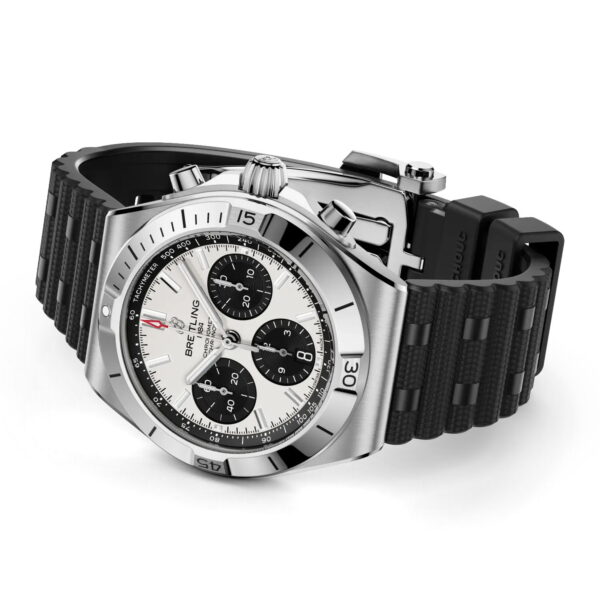 Ein Breitling Chronomat B01 Chronograph 42 aus Edelstahl mit weißem Zifferblatt, drei schwarzen Hilfszifferblättern, einer drehbaren Lünette und einem schwarzen, strukturierten Kautschukarmband, schräg auf weißem Hintergrund präsentiert.
