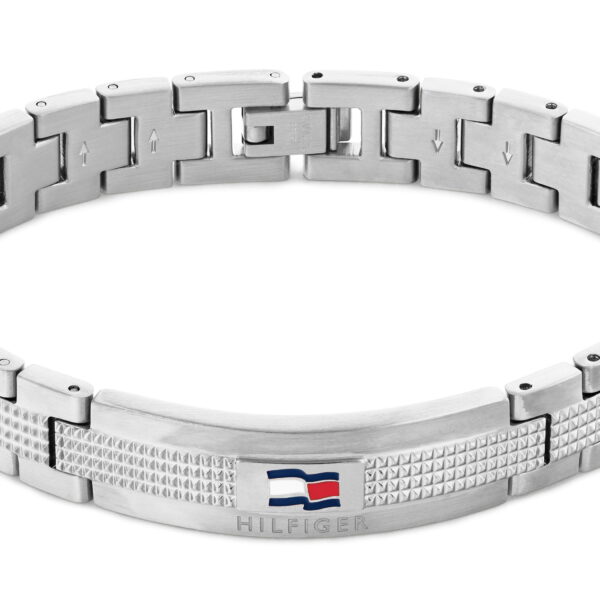 Ein silberfarbenes Metallarmband namens „Nelson“ mit strukturiertem Muster, einem kleinen Logo in Form einer rot-weiß-blauen Flagge sowie der Gravur „Hilfiger“ auf der Vorderseite.