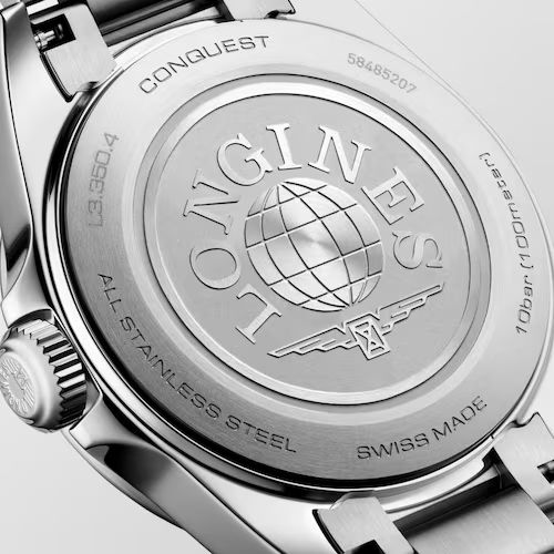 Nahaufnahme der Rückseite der Longines Conquest-Uhr mit einem Globus-Emblem und dem Logo einer geflügelten Sanduhr, die in das Edelstahlgehäuse eingraviert sind, sowie den Aufschriften „All Stainless Steel“ und „Swiss Made“.