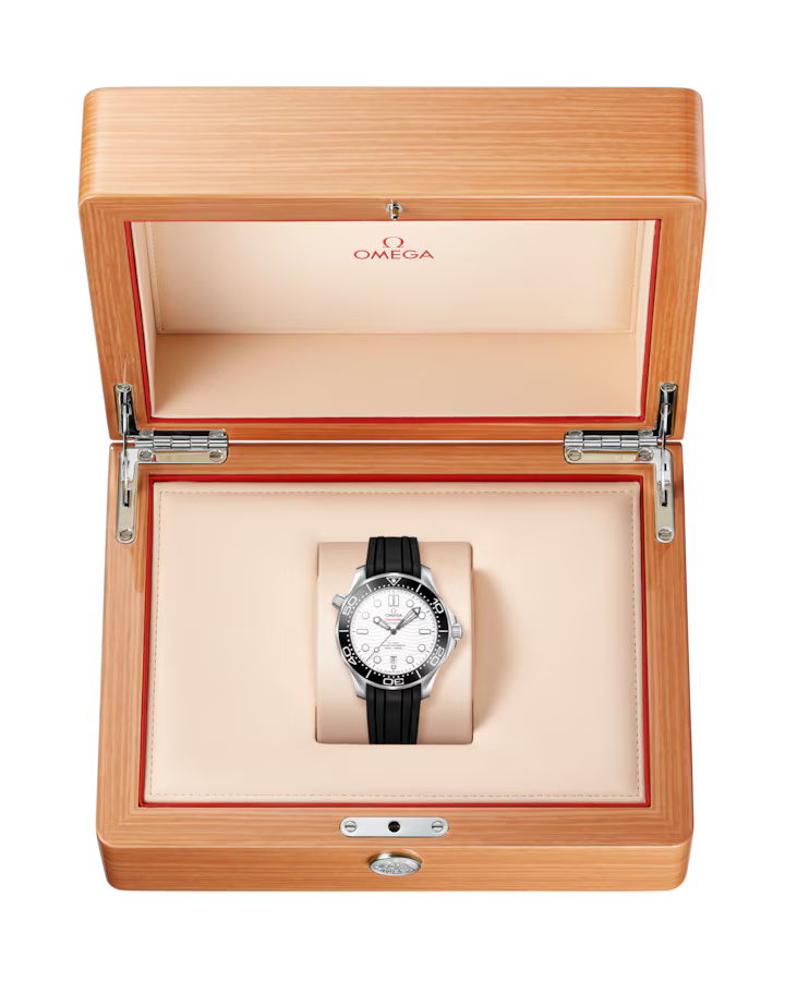 Die OMEGA Seamaster Diver 300 m 42 mm mit schwarzem Armband und silberner Lünette liegt auf einer beigen, gepolsterten Unterlage in einer offenen Uhrenbox aus Holz mit Omega-Logo.