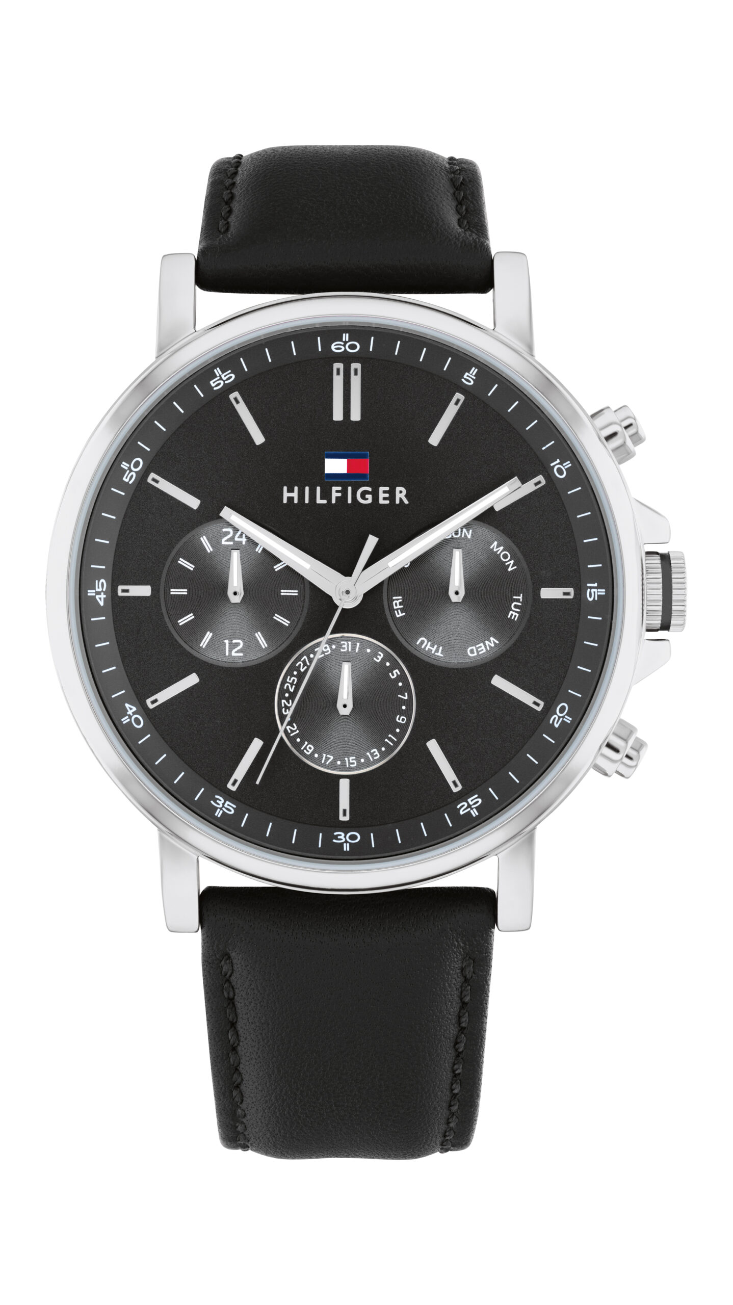 Die Tommy Hilfiger Tyson ist eine Armbanduhr aus schwarzem Leder mit einem schwarzen Zifferblatt, das drei Hilfszifferblätter, silberne Indizes und das Hilfiger-Logo unterhalb der 12-Uhr-Markierung aufweist. Sie verfügt über ein silbernes Gehäuse, das auf der rechten Seite mit zwei Drückern und einer Krone ausgestattet ist.